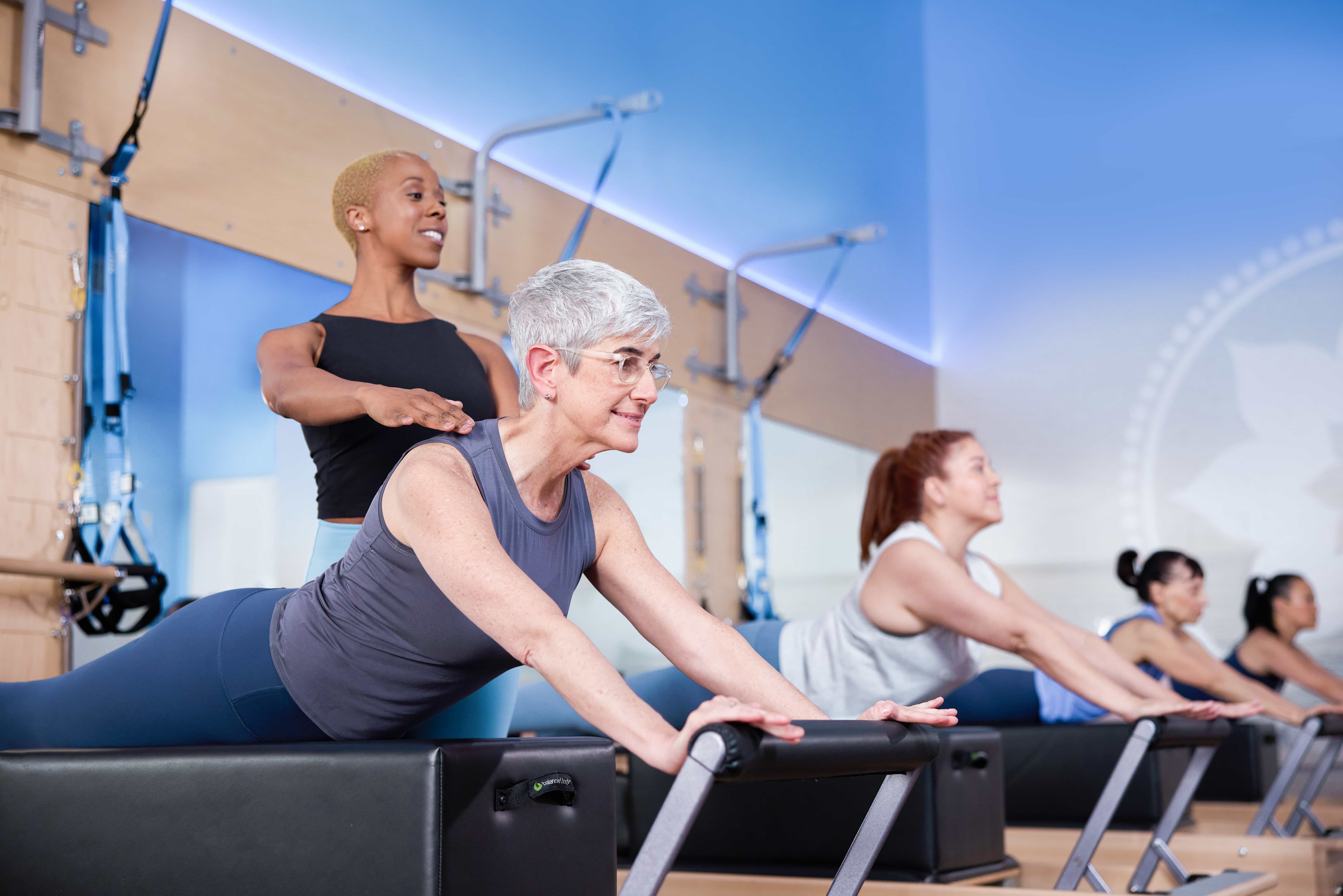 Club Pilates instructor supporting a member