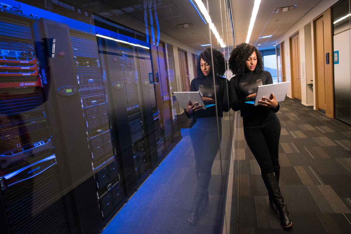 Women standing with a laptop next to a computer system