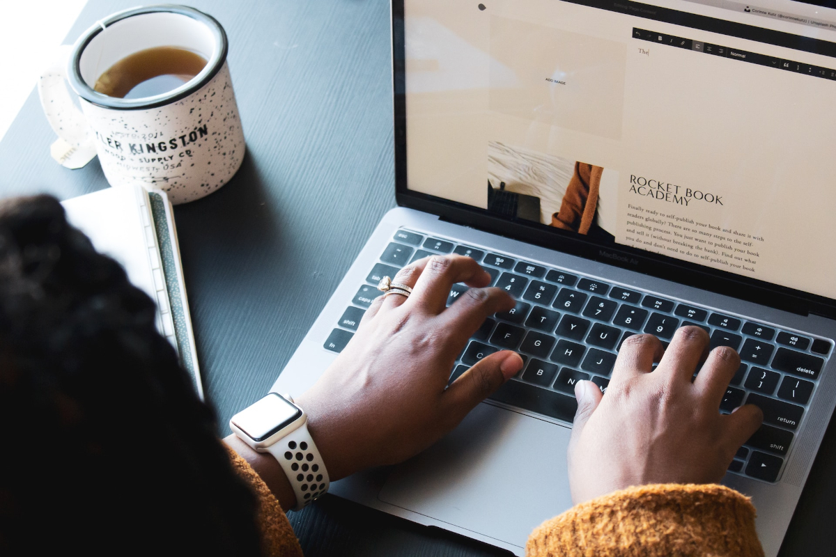 Women typing on a laptop with a cup of tea