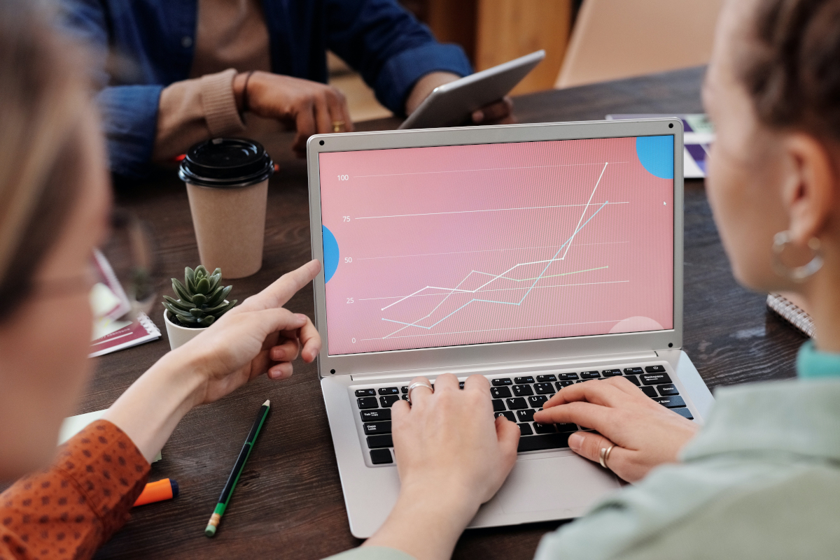 Two business women looking at a financial chart on a laptop
